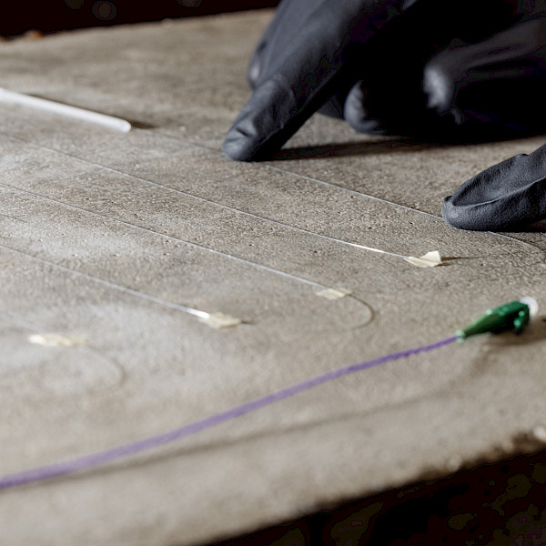 Installation von faseroptischer Messtechnik auf Beton zur kontinuierlichen Überwachung von Dehnungen und Rissen.